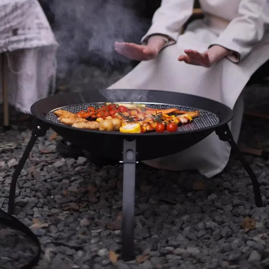 Portable outdoor camping wood stove with removable circular grill for campfire cooking, featuring a firewood burner design.